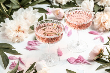 Delicious rose wine in glasses and many peony flowers. Summer celebration, wedding greeting card, invitation concept.