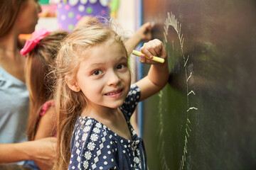 Kleines Mädchen beim malen mit Kreide an der Tafel - obrazy, fototapety, plakaty
