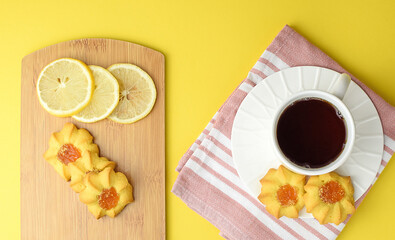 White cup of tea, homemade cookies, sliced lemon, kitchen napkin. Afternoon, dessert, tea party concept. Side and top view.