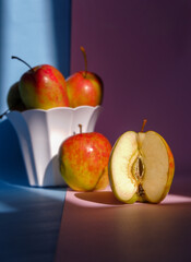 Photo of an apple in a container on a pink and blue background