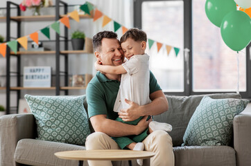 family, fatherhood and people concept - portrait of happy smiling father and little son hugging at...