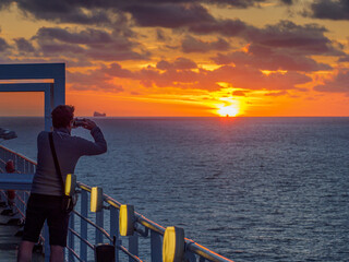 Fototapeta premium A man takes a picture of the setting sun from a ferry.