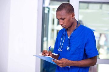 young serious doctor man taking notes on clipboard.