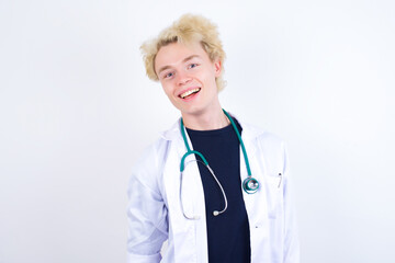 young handsome Caucasian doctor man standing against white background with broad smile, shows white teeth, feeling confident rejoices having day off.