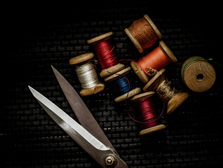 Retro sewing items: tailoring scissors, cutting knife, thimble, wooden thread spools, cushion for...