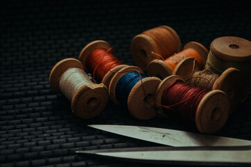 Retro sewing items: tailoring scissors, cutting knife, thimble, wooden thread spools, cushion for...