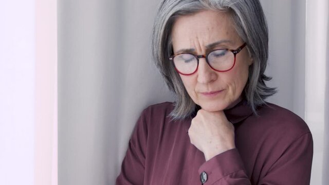 Scared nervous middle aged woman taking glance at window, suffering panic attack