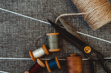 retro sewing tools: old scissors, bobbins of thread on gray fabric. Tailor's desk. manufacture of textiles or fine fabrics.