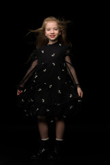 A beautiful little girl stands in the wind, her hair and clothes