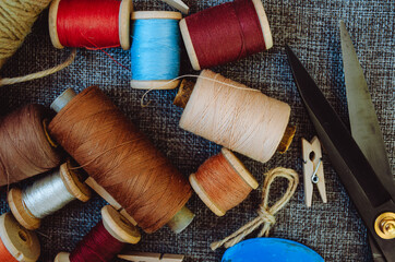 retro sewing tools: old scissors, bobbins of thread on gray fabric. Tailor's desk. manufacture of...
