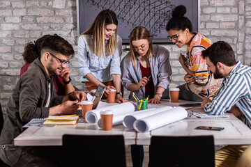 Group of young people discussing architectural designs in the creative office.