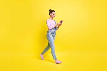 Fototapeta na wymiar Full size profile photo of optimistic nice brunet lady go look telephone wear overall isolated on yellow background