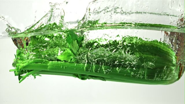 Super slow motion celery falls into the water with splashes. On a white background.Filmed on a high-speed camera at 1000 fps. High quality FullHD footage