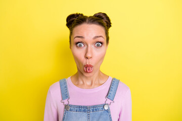 Photo of adorable childish young lady dressed jeans overall showing tongue tube isolated yellow color background