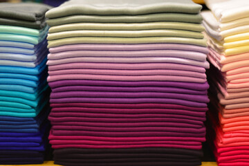 Stack of colorful t-shirts. Layers of colorful fabric. Stack of colorful folded clothes, multicolored background. Pile of bright folded clothes