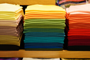 Stack of colorful t-shirts. Layers of colorful fabric. Stack of colorful folded clothes, multicolored background. Pile of bright folded clothes