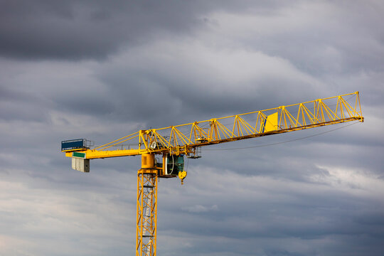 Yellow construction crane on the dark gray sky background