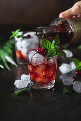 Berry alcoholic cocktail liqueur, vodka, ice and mint. Refreshing cool drink, berry liqueur or red alcoholic cocktail. - obrazy, fototapety, plakaty