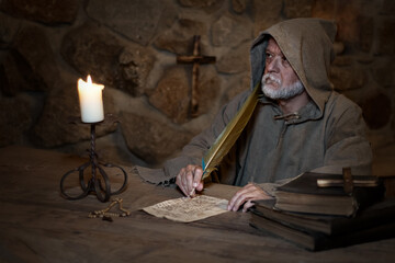Old monk writes letters in a medieval monastery