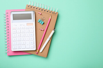 Calculator and stationery on light blue background, top view. Space for text