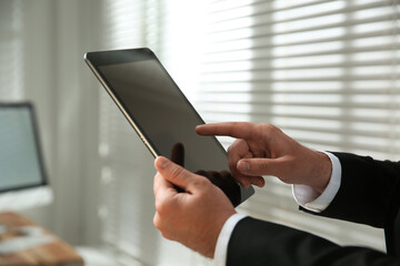 Businessman using modern tablet in office, closeup