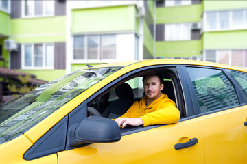 happy male taxi driver sits behind the wheel of a taxi - obrazy, fototapety, plakaty