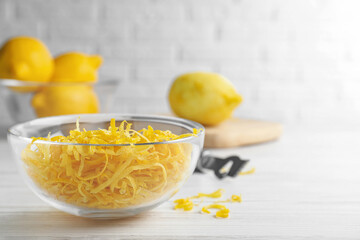 Glass bowl with fresh lemon zest on white table. Space for text