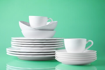 Set of clean tableware on light green background