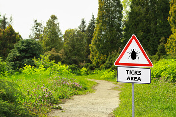 Warning sign Beware of ticks in forest on sunny day