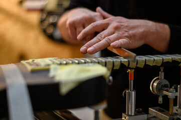 Black electrical guitar in repair service shop with a hands of a guitar luthier