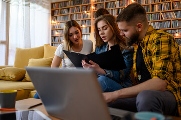 Young students using laptop while studying for their exam together at home