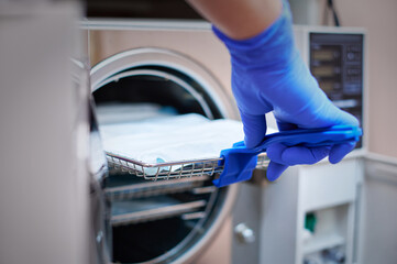 Dentist loading steel dental instruments sealed in separate airtight packaging in a steam autoclave...