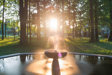 Park Dworski w Iłowej. Parkowa fontanna w ciepłym świetle zachodzącego słońca.