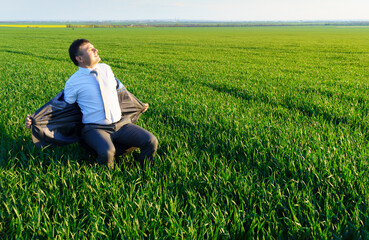 Naklejka na ściany i meble businessman sits in an office chair in a field and rests, freelance and business concept, green grass and blue sky as background
