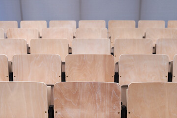 Empty collapsible wooden chairs in auditorium background. Higher education at university or college.