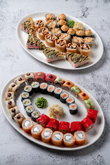 Two big trays of assorted sushi rolls on white stone background, studio light, top view above photo