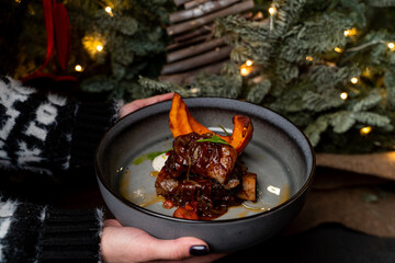 Waiter is holding a gourmet steak in a christmas decorated restaurant