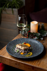 Served table in a modern seafood restaurant: fish steak with white wine aside, side view