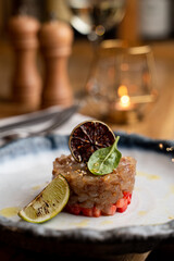 Modern fusion cuisine: fish tartar with strawberry spread and white wine, blurred restaurant in background