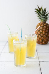 Delicious sweet refreshing pineapple juice with ice in glasses with a straw