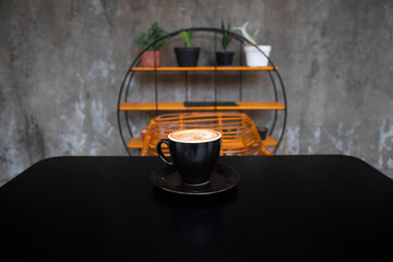 Black coffee cup on black table with round plant holder background