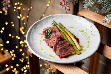 Sliced kobe rare steak with blood garnished with roasted asparagus top view in winter restaurant