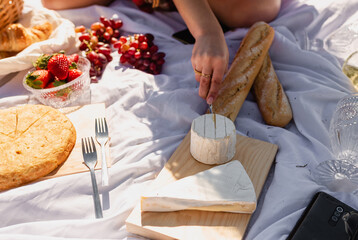 Woman cutting cheese on wooden board for picnic