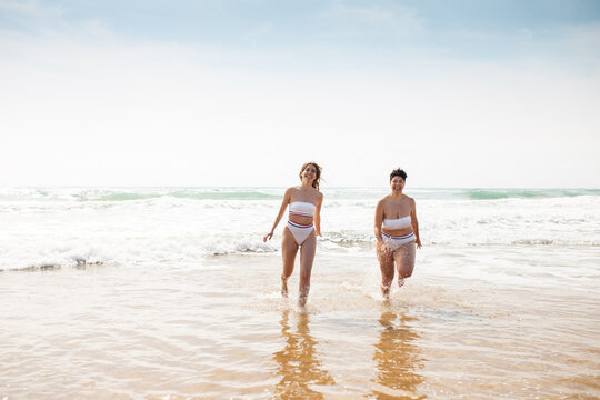 Ladies standing in sea near sandy coast