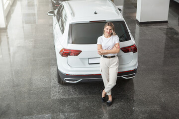 Top view shot of a female driver standing near her new SUV at car dealership, copy space