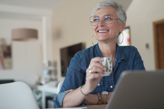 Portrait Of A 55 Year Old Senior Woman Working On Her Laptop In Her Home