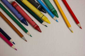 Colored pencils on white background. Lots of different colored wax pencils. Colored pencil. Pencils lie on the left. Drawing lessons, hobbies, education, creativity. Copy space. Background. Flat lay.