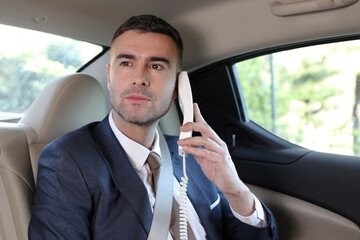 Retro businessman using telephone with cord in limousine 