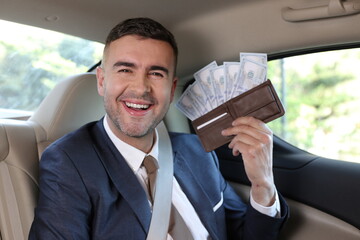 Rich businessman holding full wallet in taxi