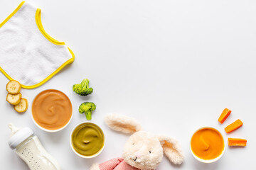 Bowls of various baby food and bottle of milk, top view